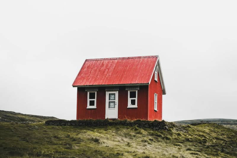 Ein rotes Haus auf einem grünen Hügel